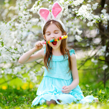 Adorable little girl eating colorful gum candies on Easter