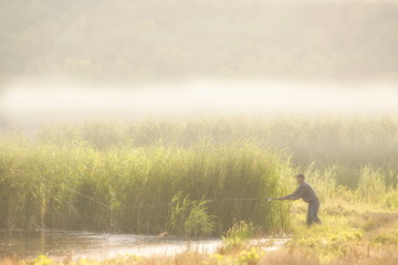 Obraz na płótnie Canvas Fisherman catches a fish in the pond.