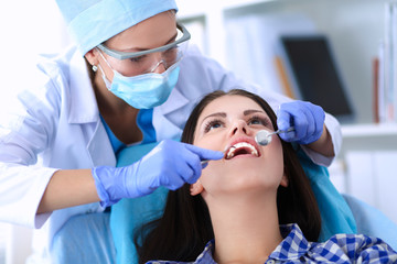 Woman dentist working at her patients teeth