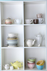 Different clean dishes on wooden shelves