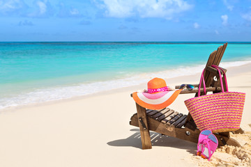 Fototapeta na wymiar Chair with bag, hat, flip-flops and sunglasses on sunny beach, t