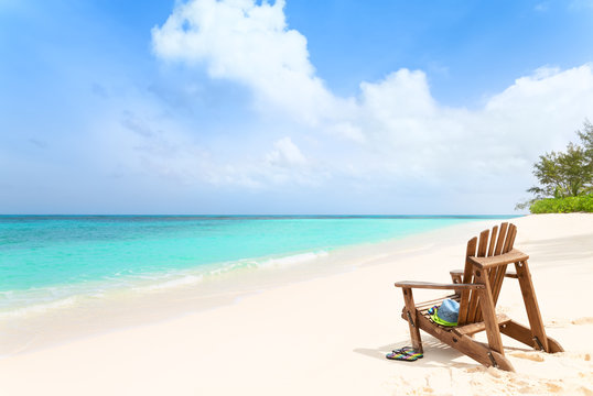 Wooden beach chair with hat and slippers at tropical beach, summ
