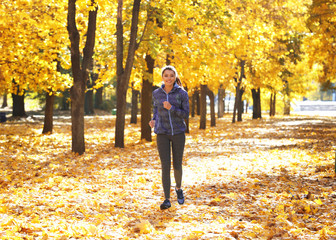 Young beautiful woman jogging in autumn park