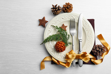 Christmas serving cutlery on plate and napkin over light wooden table