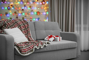 Grey couch with pillow and gifts on Christmas lights background