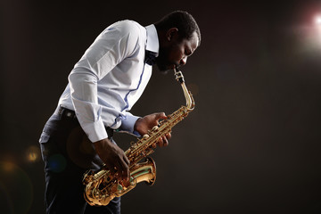 Fototapeta na wymiar African American jazz musician playing the saxophone on grey background