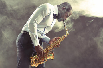 Obraz na płótnie Canvas African American jazz musician playing the saxophone against smoky background