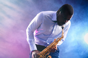 Fototapeta na wymiar African American jazz musician playing the saxophone against colorful smoky background