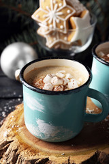 Mug of hot cacao with marshmallow and cookies on black table