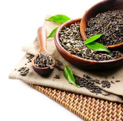 Dry tea with green leaves in wooden utensil, isolated on white