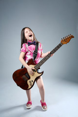 Beautiful artistic little girl playing guitar on grey background