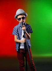 Little boy singing with microphone on a bright background