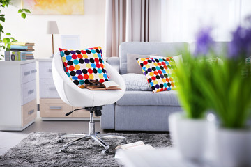 Modern living room interior in grey tones with colourful pillow on chair