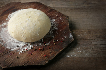 Fresh prepared dough on a wooden board, close up