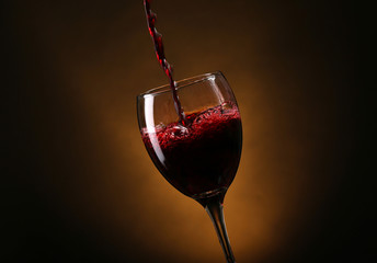Fototapeta na wymiar Wine pouring in glass on brown background