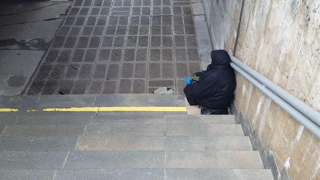Beggar woman begging on the steps of the underpass