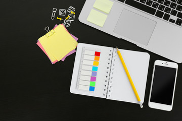 Workplace with mobile phone, laptop and stationery on black table