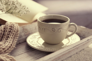 Composition of cup of tea and opened book on coffee table in the room, close up