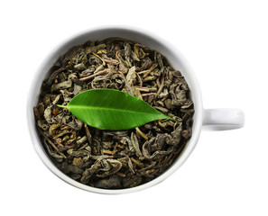 Cup with dry tea and green leaf, isolated on white