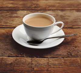 Porcelain cup of tea with milk on wooden background