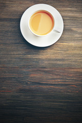 Porcelain cup of tea with milk on wooden background