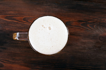 Glass of beer on wooden table, top view