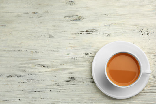 Porcelain cup of tea with milk on white wooden background