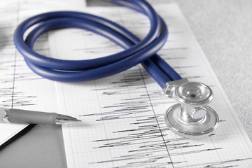 Cardiogram chart with medical stethoscope on table closeup