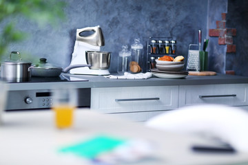 Modern white table with electric stove and utensils in the kitchen