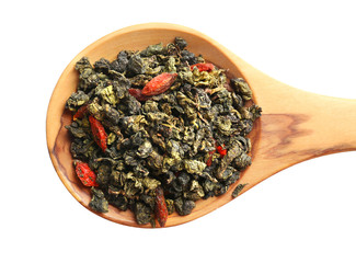 Dry tea with goji berries in wooden spoon, isolated on white