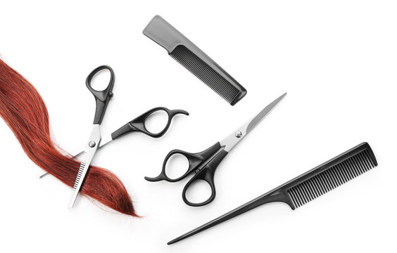 Hairdresser's scissors with combs, strand of red hair, isolated on white