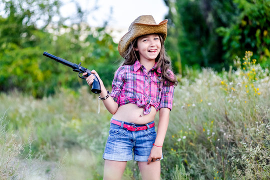 little girl with a toy gun in his hand standing in a field