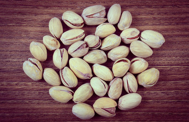 Vintage photo of pistachio nuts on wooden table, healthy eating