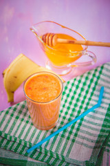 Banana smoothie and fresh banana on wooden background