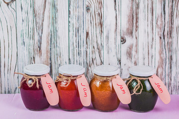 Jars of tasty jam on wooden background