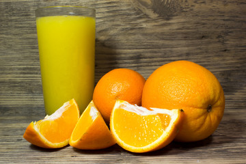 Oranges and fresh orange juice on wooden background