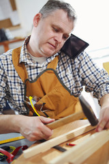 Portrait of carpenter working at his workshop and using mobile phone.
