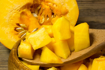 The cubes of pumpkin in wooden plate on wooden background