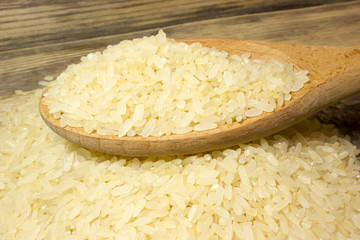 Rice grain in wooden spoon on wooden background