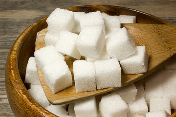 Cubes of Sugar in wooden spoon on wooden background