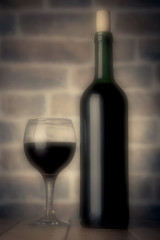 Red wine bottle and glass  on wooden table color filters blurred