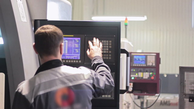 Operator working with control panel of CNC machining centerchanging numbers