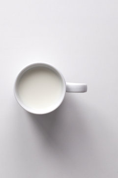 Mug of milk on white background, top view