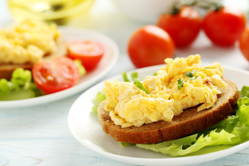 Scrambled eggs with bread and vegetables on a blue wooden table