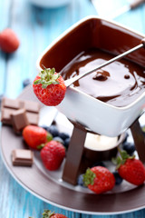 Chocolate fondue with fresh berries on a blue wooden table