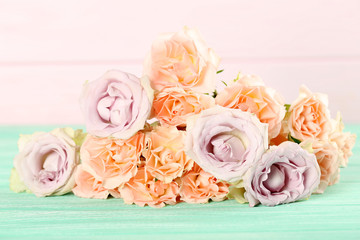 Bouquet of beautiful roses on a mint wooden table