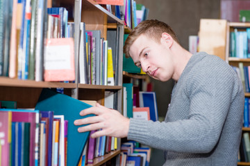 male student chooses a book in the library