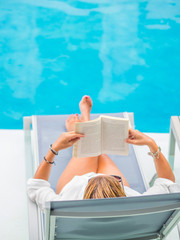 woman reading and relaxing near the swimming pool