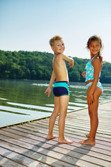 Kinder stehen auf einem Steg am See
