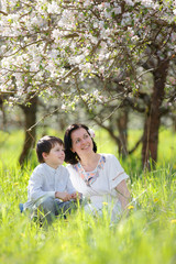 Young woman and her child having rest in spring apple garden
